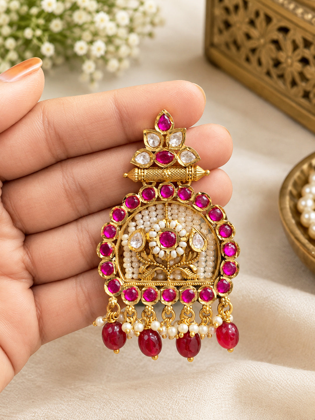 Close-up of Aurveza bridal chandbali earrings with ruby beads and pearl tassels